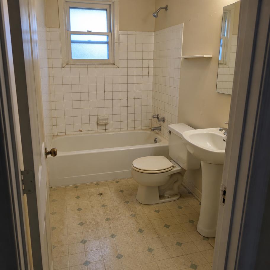 Bathroom with cracked tub surround tile before renovation